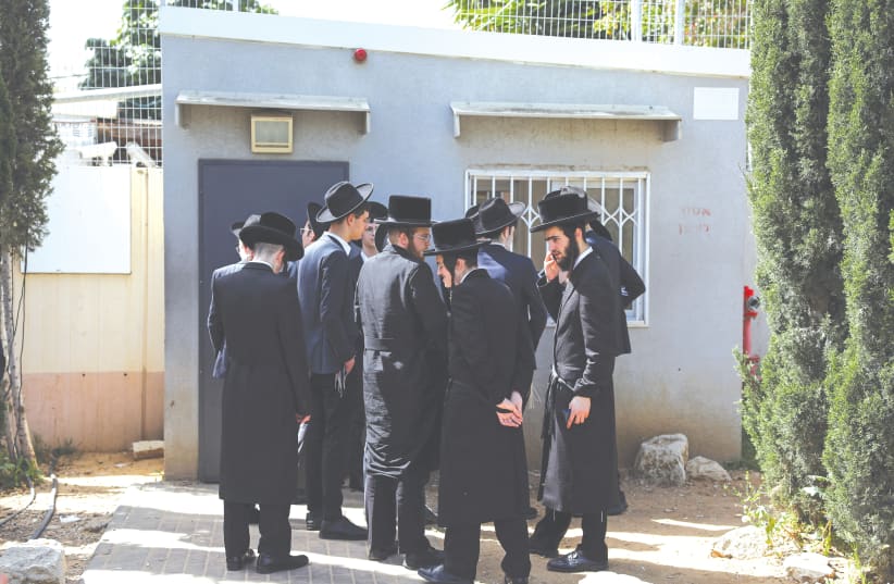  Ultra-Orthodox men line up at an IDF draft office to process their exemptions from mandatory military service. (photo credit: HANNAH MCKAY/ REUTERS)