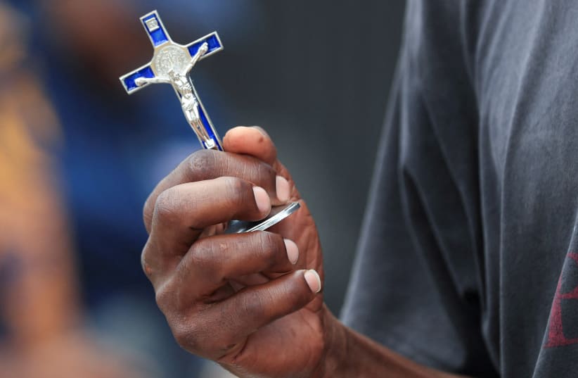 A person holds a crucifix outside a Catholic church in Harare, Zimbabwe March 29, 2024. (photo credit: PHILIMON BULAWAYO/REUTERS)