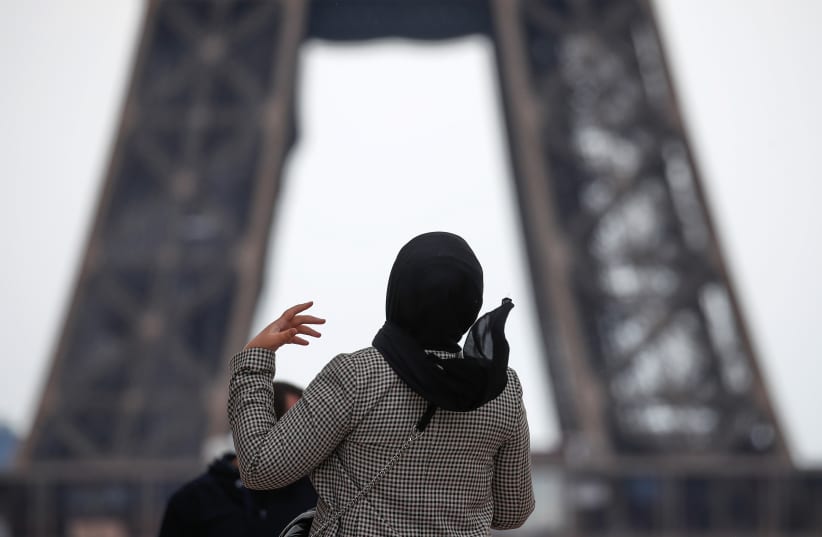  A woman wearing a hijab walks at Trocadero square near the Eiffel Tower in Paris, France, May 2, 2021. (photo credit: REUTERS/GONZALO FUENTES)