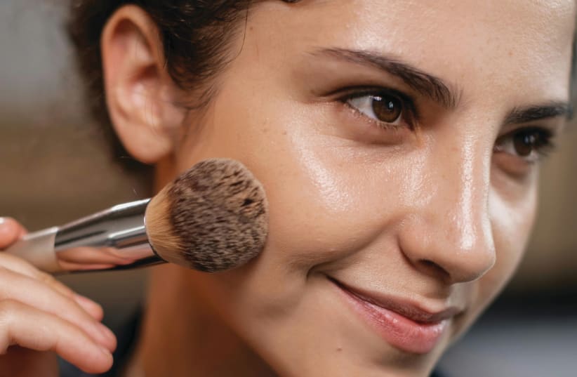   A woman applies bronzer with a brush (Illustrative) (photo credit: PEXELS)