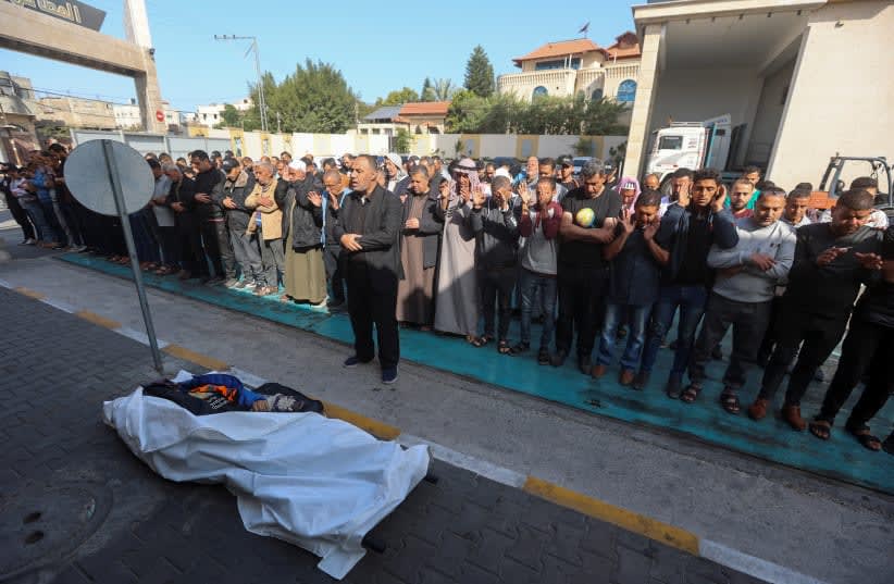  Dolientes ofrecen oraciones fúnebres junto al cadáver del palestino Issam Abu Taha, trabajador de la World Central Kitchen (WCK), muerto en un ataque aéreo israelí. (photo credit: REUTERS/AHMED ZAKOT)