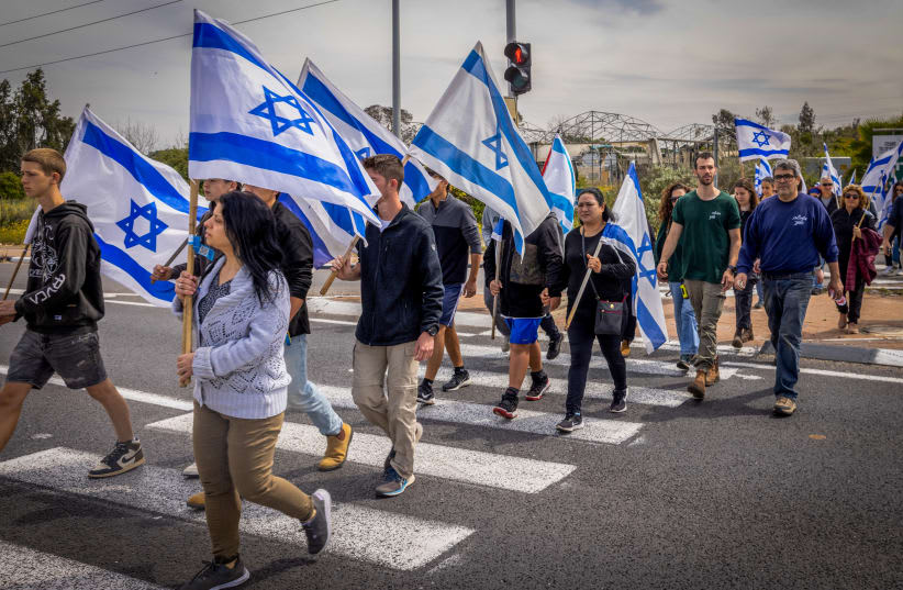 Israelíes sostienen banderas israelíes mientras se dirigen al funeral del soldado israelí sargento mayor Ilay David Garfinkel, cerca de Moshav Sitria, el 24 de marzo de 2024. (photo credit: Yossi Aloni / Flash90)
