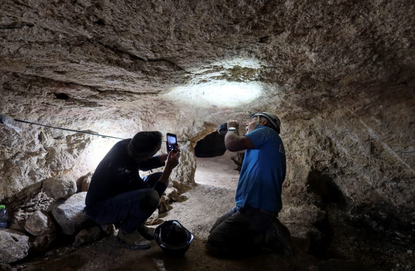 A marking on the ceiling of a cave is inspected as part of an immense underground hideout comprising narrow tunnels and large storage spaces that was dug by Jewish villagers nearly 2,000 years ago at a time of revolt against the Roman Empire, in Huqoq, northern Israel April 1, 2024. (photo credit: REUTERS/Ari Rabinovitch)