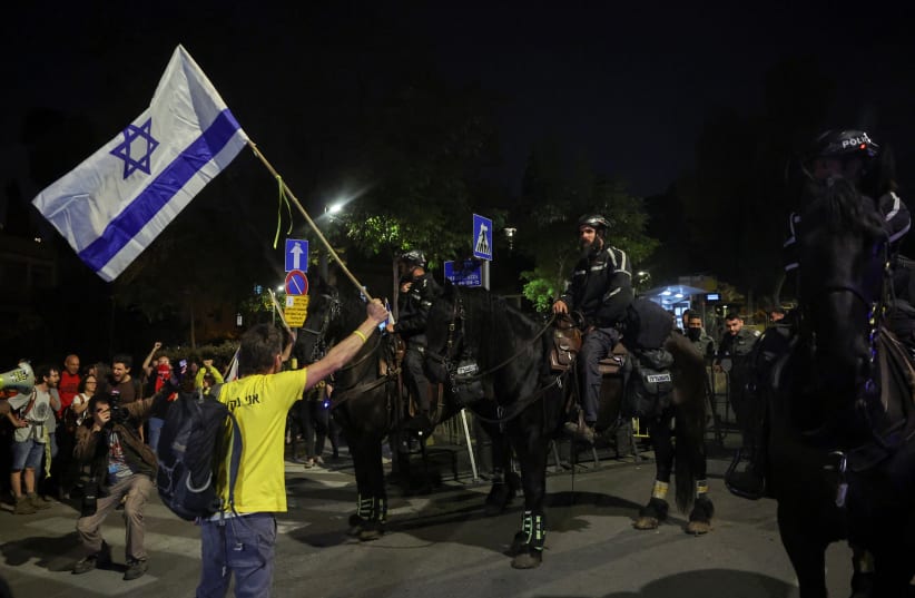  A protester waves an Israeli flag near Prime Minister Benjamin Netanyahu's residence, during a demonstration calling for his ouster, in the wake of the deadly October 7 attack on Israel by the Palestinian Islamist group Hamas and the ensuing war in Gaza, in Jerusalem, April 2, 2024.  (photo credit: RONEN ZVULUN/REUTERS)