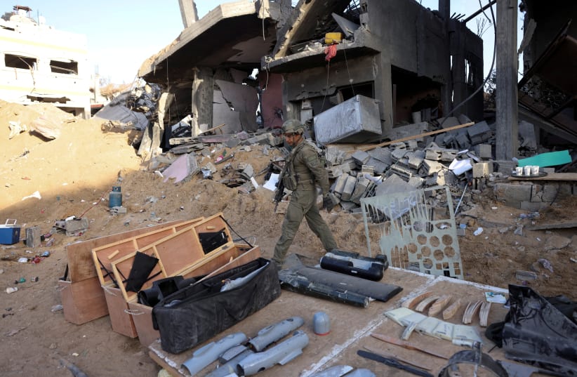 An Israeli soldier walks next to items found inside a workshop which they claim was used for weapon production and located on the lower floors of a residential building in the northern Gaza Strip, November 8, 2023. (photo credit: RONEN ZVULUN/REUTERS)