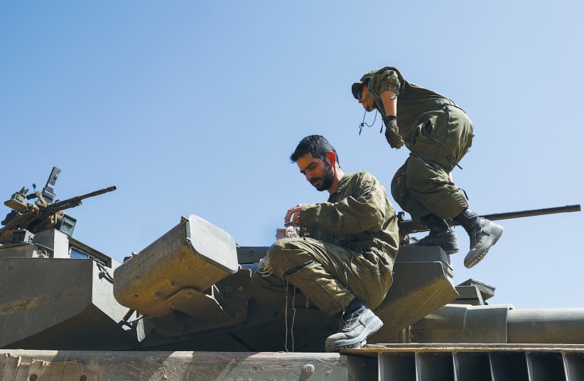  IDF SOLDIERS conduct maintenance work on a Merkava tank, on the Israeli side of the Gaza border this week. The Israeli government must instruct the army on how to proceed, for time is inexorable and the imprint of the IDF’s impressive achievements is fast fading, the writer warns. (photo credit: Hannah McKay/Reuters)