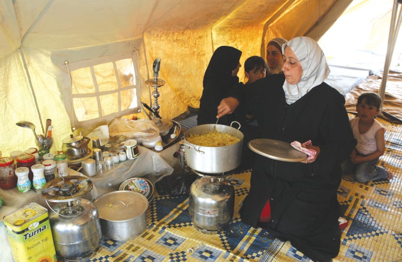  A REFUGEE COOKS inside a tent in the Al-Hawl refugee camp, in northern Syria, in this file photo.  (photo credit: REUTERS/KHALED AL-HARIRI)