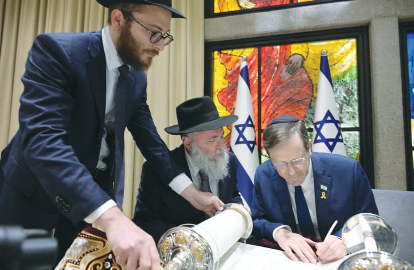  PRESIDENT ISAAC HERZOG writes the final letter in the Kiev Torah scroll, without the hand-guidance of a scribe. (photo credit: AMOS BEN GERSHOM/GPO)