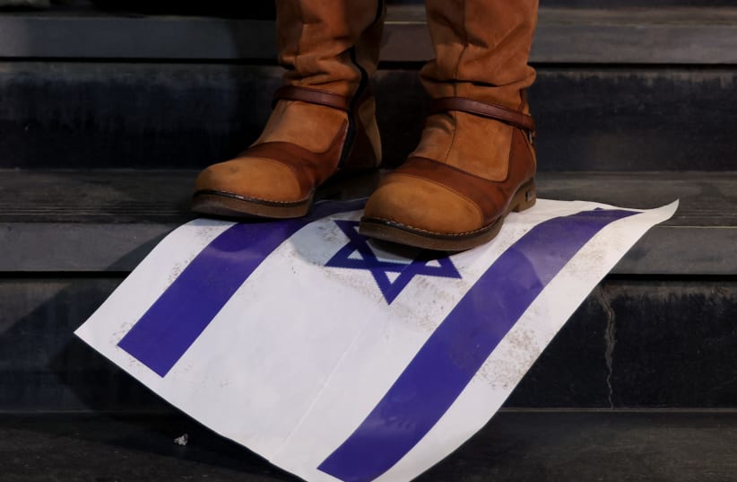 A person steps on a placard depicting an Israeli flag as demonstrators protest against Israel and in support of Palestinians, during a demonstration to mark 100 days since the start of the ongoing conflict between Israel and the Palestinian Islamist group Hamas, in front of the Egypt Journalists Syn (photo credit: AMR ABDALLAH DALSH / REUTERS)