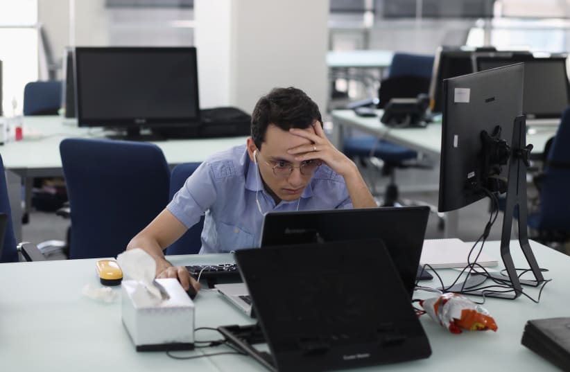  An employee of a stock brokerage firm monitors stock prices on his computer, following the outbreak of the coronavirus disease (COVID-19), at a brokerage house in Tehran, Iran, May 12, 2020. (photo credit: ALI KHARA/WANA (WEST ASIA NEWS AGENCY)/VIA REUTERS)