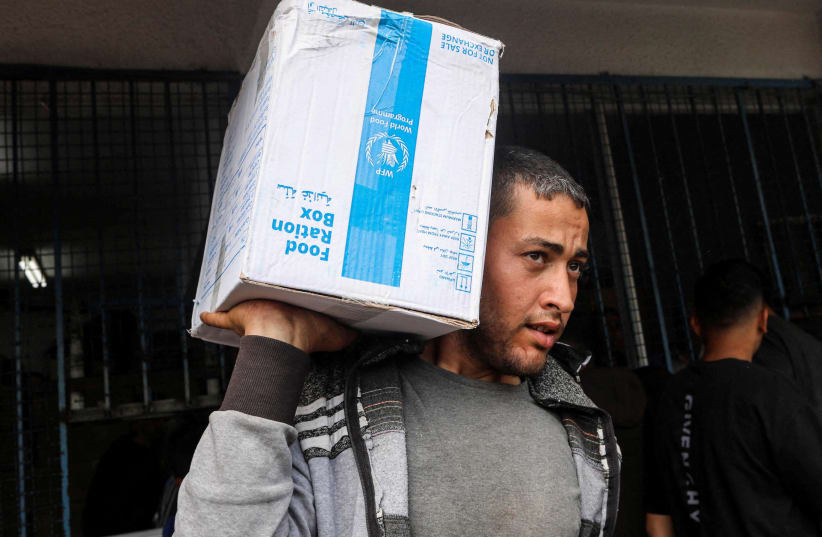  A Palestinian carries a box of aid distributed before Eid al-Fitr holiday, which marks the end of the Muslim holy fasting month of Ramadan, amid the ongoing conflict between Israel and Hamas, in Deir Al-Balah, in the central Gaza Strip April 8, 2024.  (photo credit: REUTERS/Ramadan Abed)