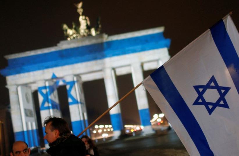 La Puerta de Brandemburgo de Berlín (Alemania) se ilumina con los colores de la bandera israelí para mostrar su solidaridad con Israel. (photo credit: REUTERS)