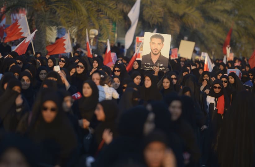   Manifestantes antigubernamentales sostienen una foto de un preso político mientras piden su liberación durante una concentración organizada por el principal partido de la oposición de Bahréin, Al Wefaq, en Budaiya, al oeste de Manama, 15 de febrero de 2014. (photo credit: REUTERS)