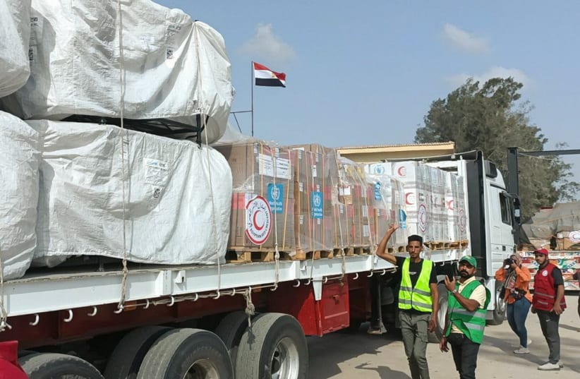 Miembros y voluntarios de la Media Luna Roja Egipcia se reúnen junto a un camión que transporta ayuda humanitaria mientras atraviesa el cruce de Rafah desde el lado egipcio, en medio del conflicto en curso entre Israel y Hamas, en Rafah, Egipto, el 22 de octubre de 2023. (photo credit: REUTERS/STRINGER)