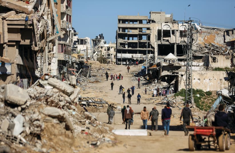  PALESTINOS CAMINAN junto a las ruinas de las casas destruidas durante la guerra de Gaza, en la ciudad de Gaza, el mes pasado. (photo credit: REUTERS/DAWOUD ABU ALKAS)