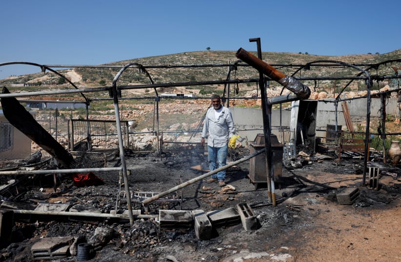 A Palestinian man inspects the damage to a house after Israeli settlers attacked the village of al-Mughayyer, in the West Bank, April 13, 2024 (photo credit: MOHAMAD TOROKMAN/REUTERS)