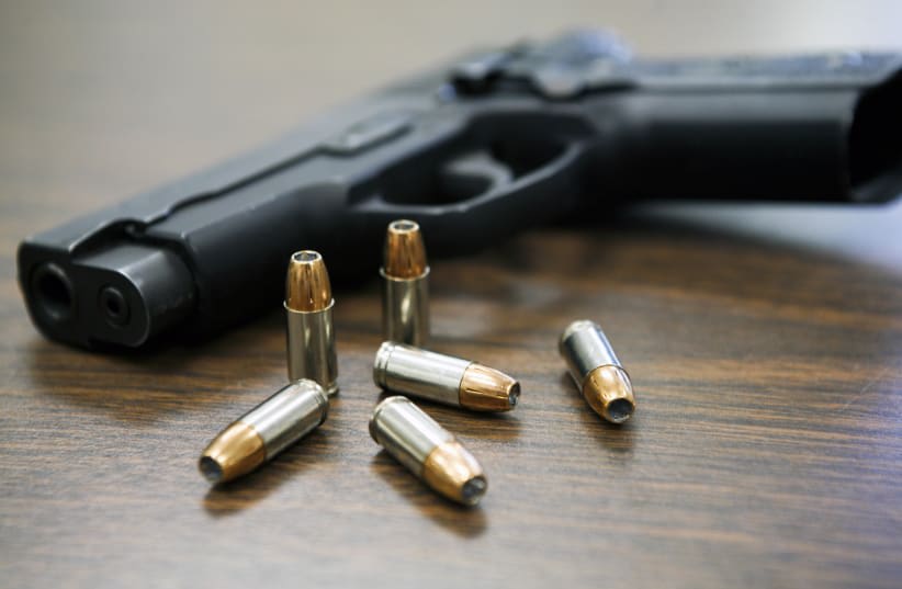  Una pistola con balas sobre la mesa. (photo credit: Wikimedia Commons)
