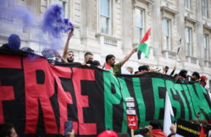 Manifestantes pro Palestina sostienen una pancarta, mientras se manifiestan frente a Downing Street en Londres, Gran Bretaña, el 12 de junio de 2021.  (photo credit: REUTERS/HENRY NICHOLLS)
