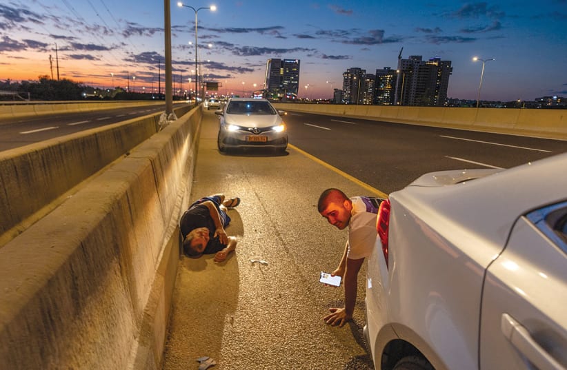  Taking cover on the highway amid the fire of aerial threats. (photo credit: FLASH90)