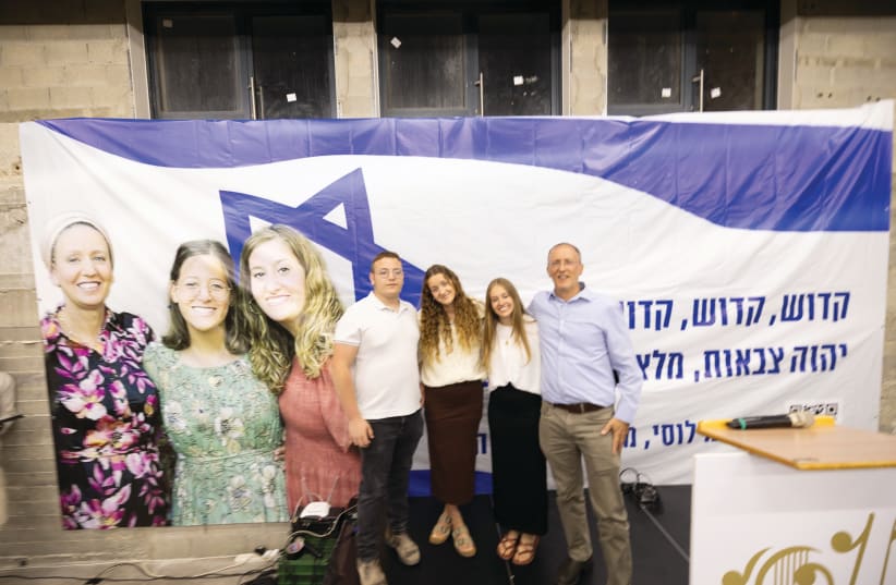  SHIRAT LUCY: Yehuda, Keren, Tali, and Rabbi Leo Dee in front of a portrait of Lucy, Rina, and Maia, at the first yahrzeit event, April 7. (photo credit: Yacov Segal)
