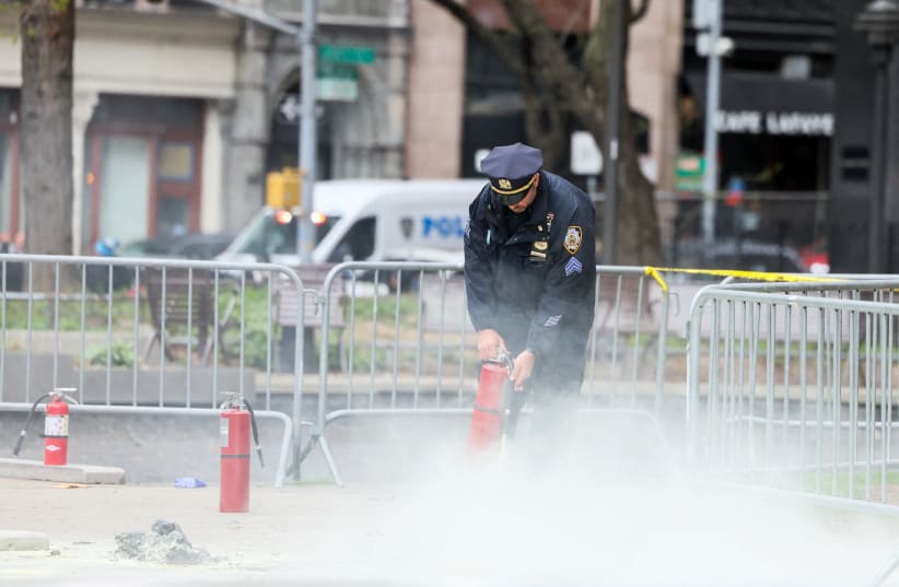  A police officer uses a fire extinguisher as emergency personnel respond to a report of a person covered in flames, outside the courthouse where former U.S. President Donald Trump's criminal hush money trial is underway, in New York, US, April 19, 2024. (photo credit: REUTERS/BRENDAN MCDERMID)