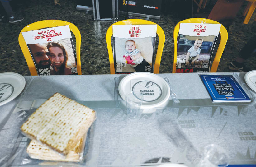  Photos of the Bibas family, thought to be held hostage in Gaza, are seen at a Passover ceremony in Kibbutz Nir Oz, on April 11, 2024. (photo credit: AMIR COHEN/REUTERS)