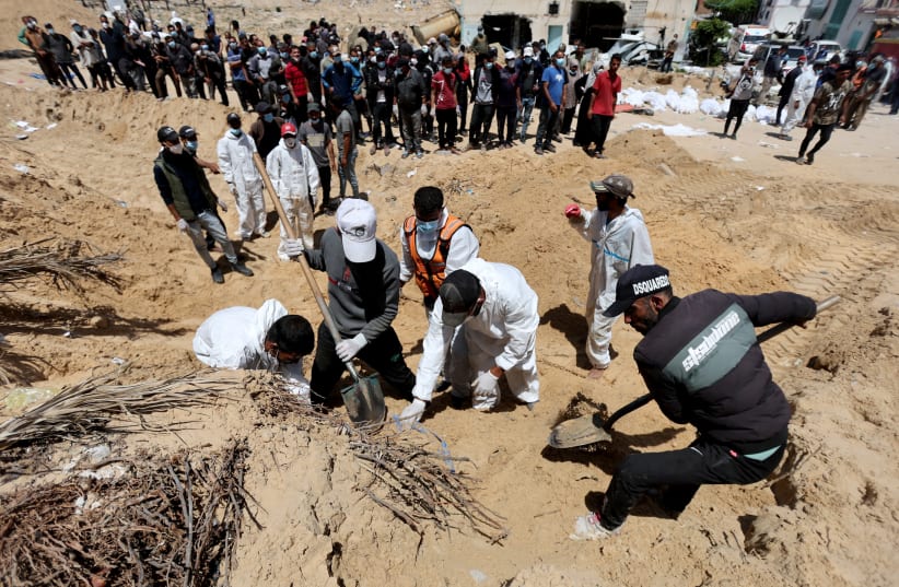 People work to move into a cemetery bodies of Palestinians killed during Israel's military offensive and buried at Nasser hospital, amid the ongoing conflict between Israel and Hamas, in Khan Yunis in the southern Gaza Strip, April 21, 2024. (photo credit: REUTERS/Ramadan Abed)