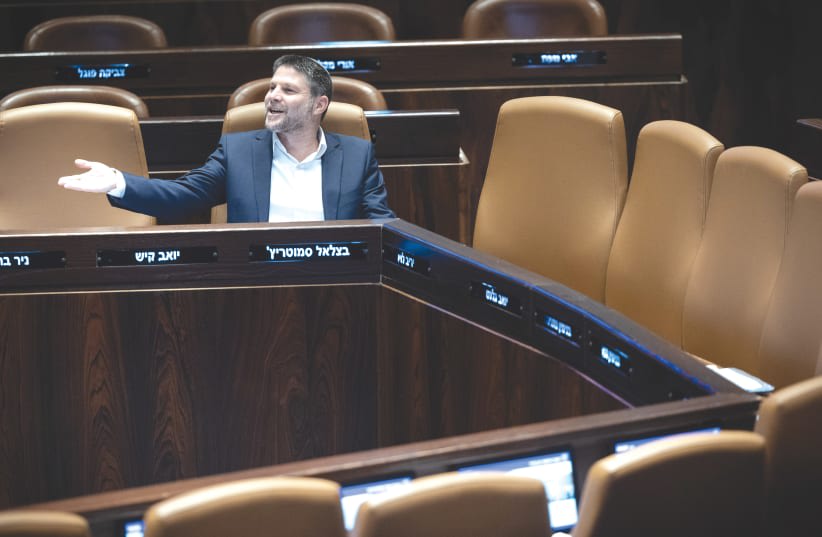  EL MINISTRO DE FINANZAS, Bezalel Smotrich, sentado entre los asientos vacíos de la mesa del gabinete en el pleno de la Knesset. Una parte importante de nuestro problema es la estructura de nuestro sistema parlamentario, que hace de las asignaciones ministeriales una recompensa por la lealtad al par (photo credit: YONATAN SINDEL/FLASH90)