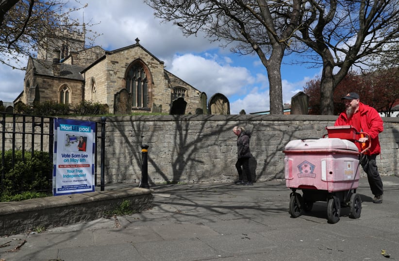  People walk past an election poster ahead of tomorrow's local elections, in Hartlepool, Britain May 5, 2021. (photo credit: REUTERS/LEE SMITH)