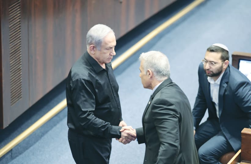  PRIME MINISTER Benjamin Netanyahu and opposition leader Yair Lapid shake hands in the Knesset plenum, in October. It’s imperative to reach an agreement on the establishment of a national emergency government, with the participation of all Zionist factions, the writer argues.  (photo credit: NOAM REVKIN FENTON/FLASH90)
