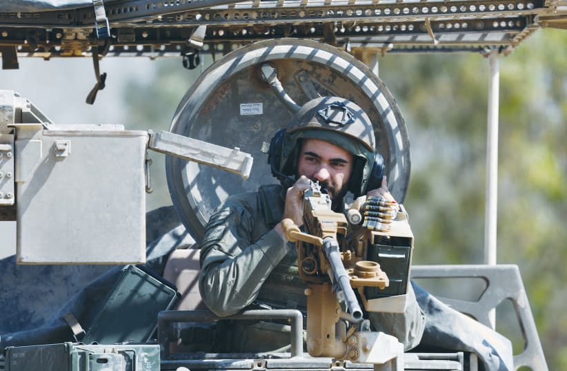  AN IDF soldier on a military vehicle near the Gaza border last week; The low ratio of civilian-to-combatant deaths is noteworthy as the war is fought in dense urban areas where civilians have little protection, and Hamas fighters are protected in underground tunnels, says the writer. (photo credit: AMIR COHEN/REUTERS)
