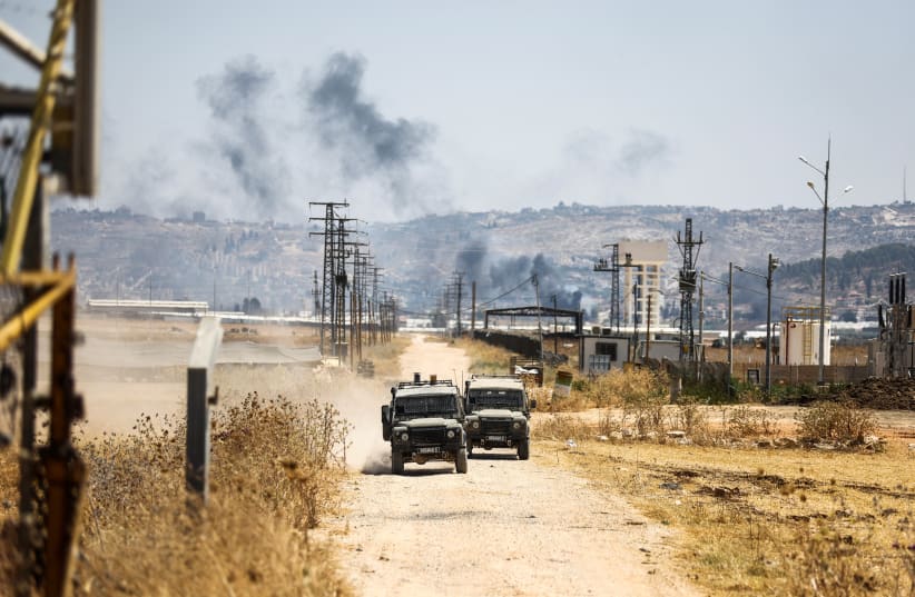 Jeeps militares israelíes circulan por una carretera que conduce a una incursión en el campo de refugiados de Yenín, vista desde el puesto de control de Salem, la entrada desde Israel a Yenín, en Cisjordania, el 3 de julio de 2023. (photo credit: RONEN ZVULUN/REUTERS)