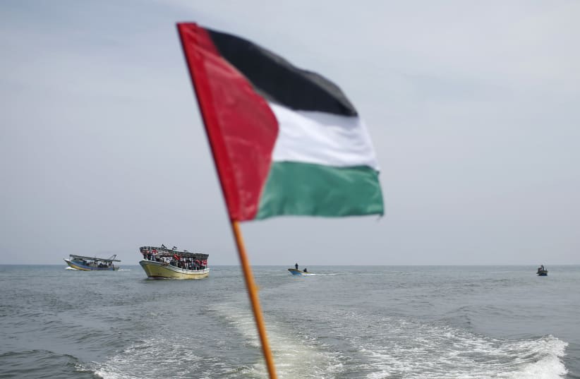  Una bandera palestina ondea mientras activistas montan en un barco durante una concentración previa al cuarto aniversario del incidente de la flotilla de Gaza Mavi Marmara, en el puerto marítimo de la ciudad de Gaza el 29 de mayo de 2014. (photo credit: REUTERS/MOHAMMED SALEM)