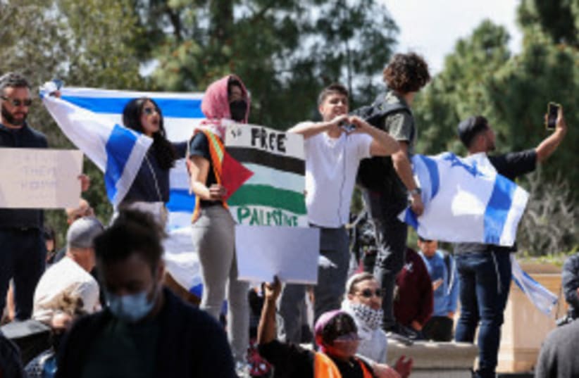 Manifestantes proisraelíes sostienen banderas mientras los estudiantes de una acampada protestan en apoyo de los palestinos, en medio del actual conflicto entre Israel y Hamás, en la Universidad de California en Los Ángeles, California, Estados Unidos. 25 de abril de 2024. (photo credit: MIKE BLAKE/REUTERS)