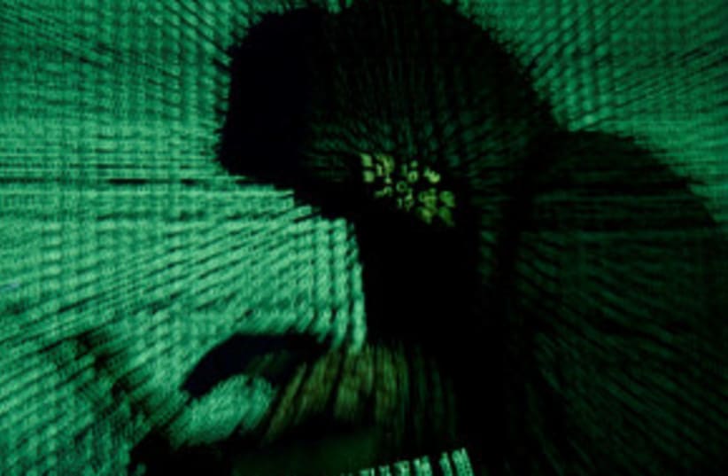 Un hombre sostiene un ordenador portátil mientras se proyecta sobre él un código cibernético en esta imagen ilustrativa tomada el 13 de mayo de 2017. (photo credit: KACPER PEMPEL/ILLUSTRATION PHOTO/REUTERS)