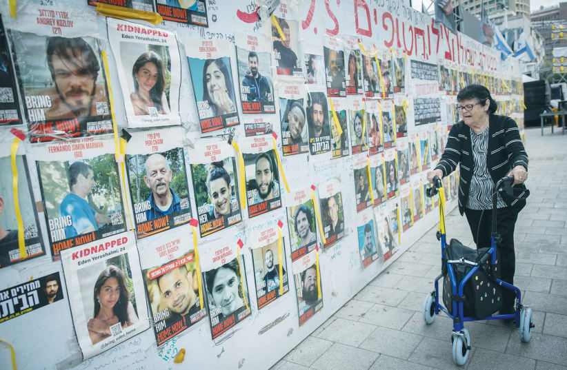  A WOMAN looks at photos of hostages posted at Hostages Square in Tel Aviv. Either by a deal or by force, the hostages must be returned as part of resolving the current crisis, the writer asserts. (photo credit: MIRIAM ALSTER/FLASH90)