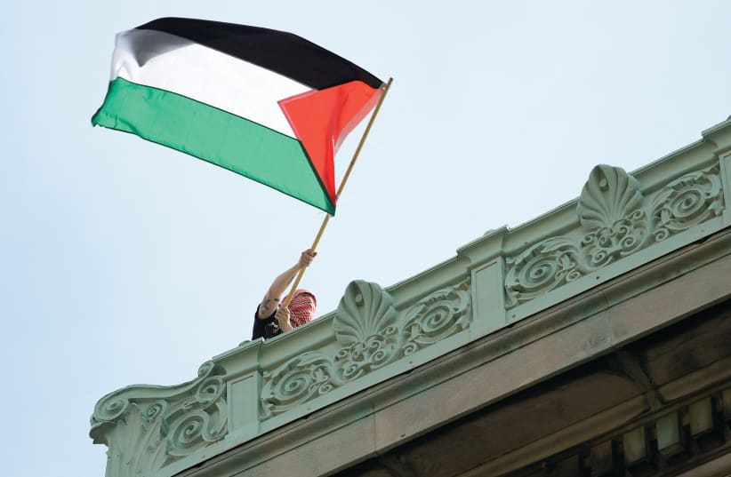  A STUDENT protester waves a Palestinian flag above Hamilton Hall on the campus of Columbia University in New York, in late April. (photo credit: MARY ALTAFFER/REUTERS)