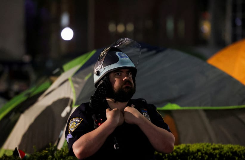  An NYPD law enforcement official stands guard after establishing a closed perimeter on campus around student protesters at Columbia University during a comprehensive operation to clear campus of protesters in support of Palestinians (photo credit: REUTERS/CAITLIN OCHS/FILE PHOTO)