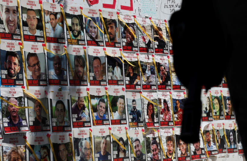  An Israeli soldier's rifle is silhouetted next to posters of hostages kidnapped during the deadly October 7 attack, in Tel Aviv, Israel, May 5, 2024 (photo credit: REUTERS/SHANNON STAPLETON)