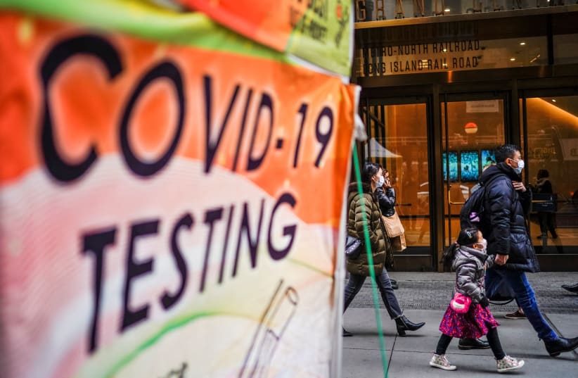  People wearing masks walk next to coronavirus disease (COVID-19) testing site in New York City, New York, U.S., December 12, 2022. (photo credit: EDUARDO MUNOZ / REUTERS)