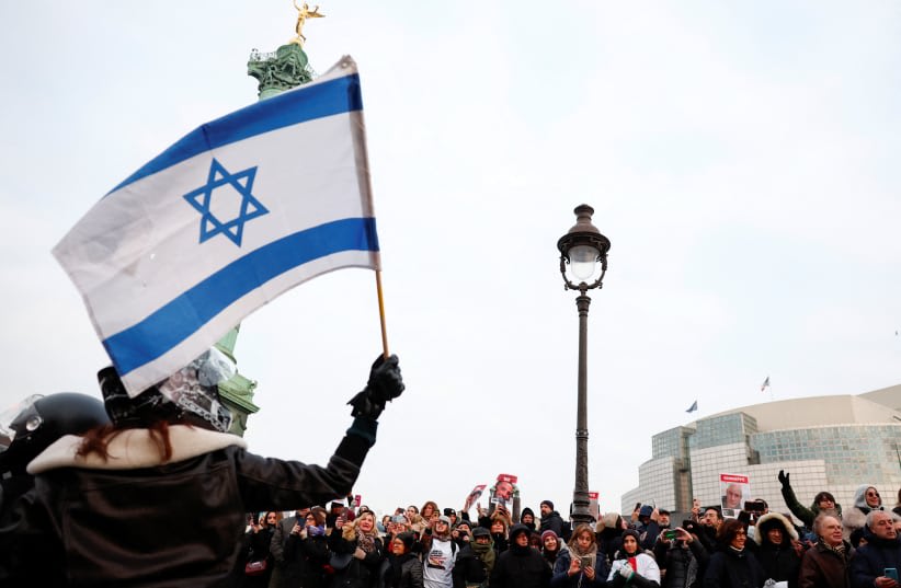  Una mujer agita una bandera israelí mientras la gente se reúne durante el evento "100 días 100 voces" para conmemorar los 100 días desde el ataque del 7 de octubre de Hamas, pidiendo la liberación de los rehenes israelíes en Gaza, frente a la Ópera Bastilla en París, Francia, 14 de enero de 2024. (photo credit: REUTERS/GONZALO FUENTES)