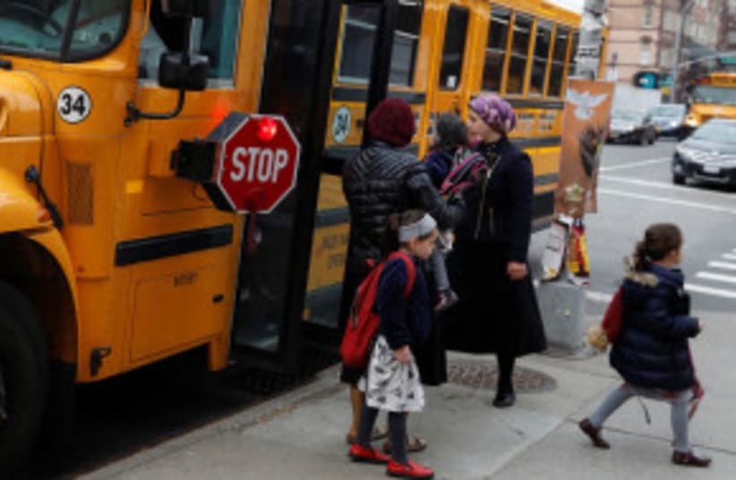 Niños judíos ortodoxos bajan de un autobús escolar en Williamsburg, Brooklyn, durante la emergencia de salud pública por sarampión declarada por el alcalde Bill de Blasio (photo credit: REUTERS/SHANNON STAPLETON)