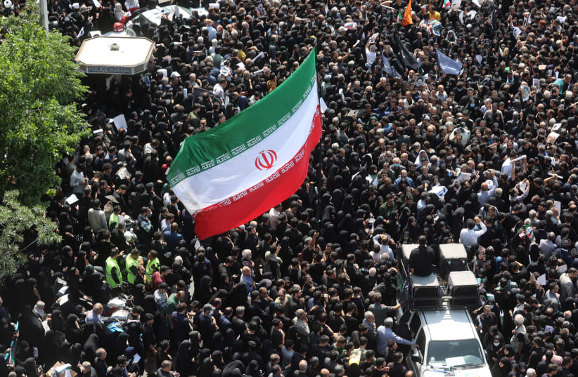  Mourners hold up an Iranian flag as they attend the funeral of Iran's President Ebrahim Raisi, Foreign Minister Hossein Amirabdollahian and others, in Tehran, Iran, May 22, 2024. (photo credit: MAJID ASGARIPOUR/WANA (WEST ASIA NEWS AGENCY) VIA REUTERS)