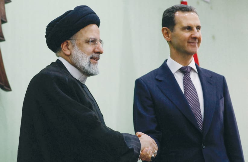  SYRIA’S PRESIDENT Bashar Assad shakes hands with Iranian President Ebrahim Raisi during the signing of a cooperation agreement in Damascus, last year. The ICC has never issued an arrest warrant against Ayatollah Khamenei or Assad, the writer points out. (photo credit: YAMAM AL SHAAR/REUTERS)