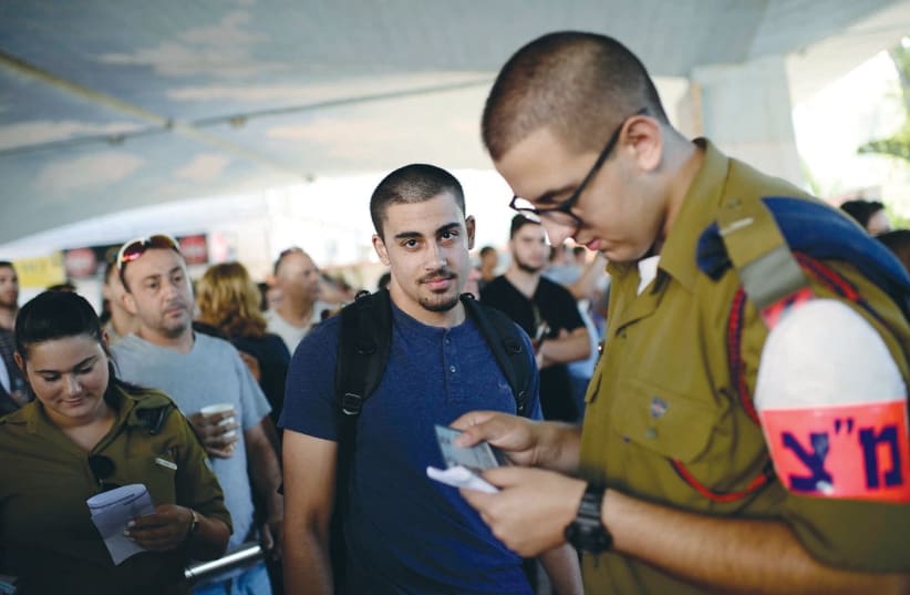  Un MIEMBRO de la Policía Militar comprueba el documento de identidad de un soldado que se alista, en el cuartel general de reclutamiento de las FDI en Tel Hashomer. (photo credit: TOMER NEUBERG/FLASH90)