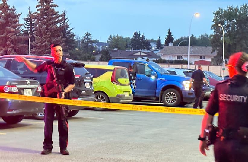  Un oficial de policía habla con el personal de seguridad después de un tiroteo en el West Edmonton Mall en Edmonton, Alberta, Canadá 21 de agosto 2023 (photo credit: REUTERS)