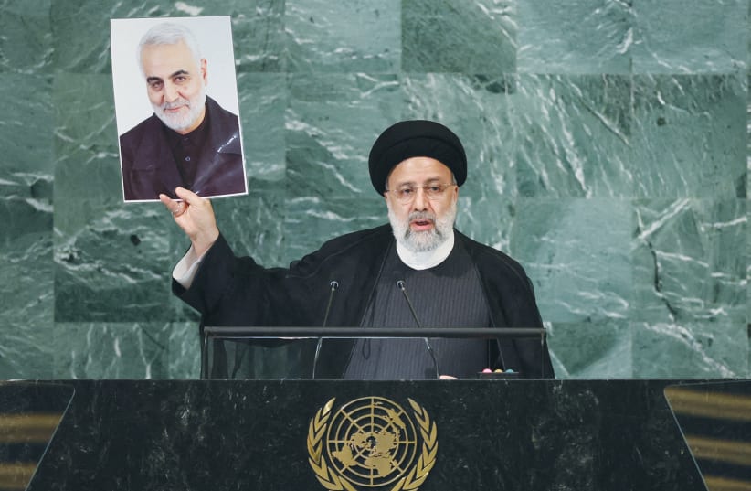  THEN-IRANIAN PRESIDENT Ebrahim Raisi holds up a picture of former Quds Force commander Qasem Soleimani, killed in a US attack, as he addresses the UN General Assembly, in 2022. (photo credit: BRENDAN MCDERMID/REUTERS)