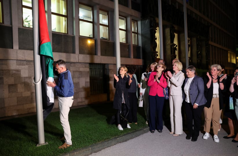 A man puts up the flag of Palestine as members of parliament applaud after the Slovenian parliament approved the recognition of an independent Palestinian state, in Lubljana, Slovenia June 4, 2024. (photo credit: REUTERS/BORUT ZIVULOVIC)