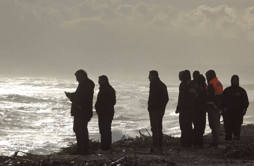  Rescatistas trabajan en la playa donde se encontraron cuerpos de refugiados tras un naufragio, en Cutro, la costa oriental de la región italiana de Calabria, Italia, 26 de febrero de 2023, en esta captura de pantalla tomada de un vídeo de Reuters TV. (photo credit: REUTERS TV/via REUTERS)
