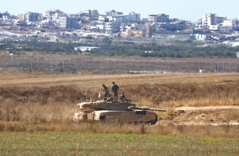  IDF SOLDIERS stand on top of a tank near the Israel-Gaza border, this week. Among the many disingenuous and ahistorical narratives, says the writer, is that Israel has done enough harm to Hamas, and should allow it to perhaps even remain in power in Gaza.  (photo credit: AMIR COHEN/REUTERS)